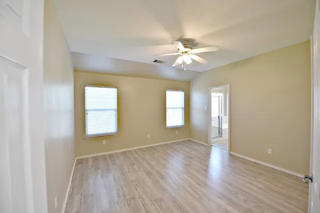 a view of an empty room with a window and wooden floor