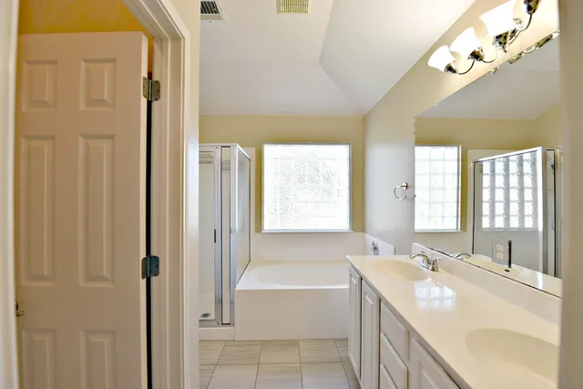 a spacious bathroom with a tub sink and mirror