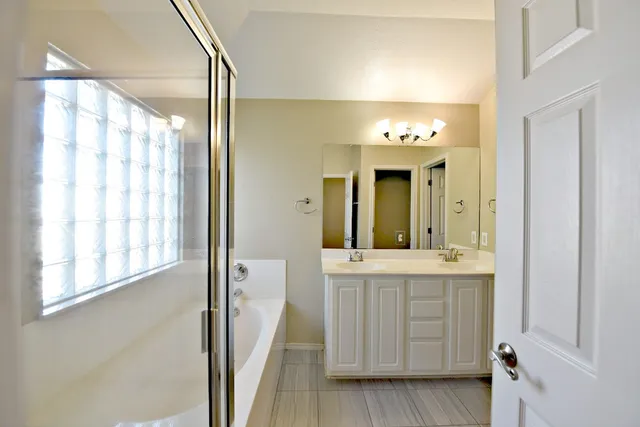 a bathroom with a double vanity sink and mirror with shower