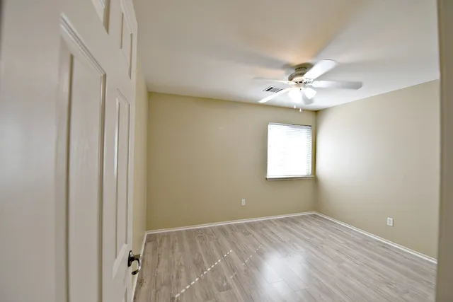 an empty room with a window and a ceiling fan
