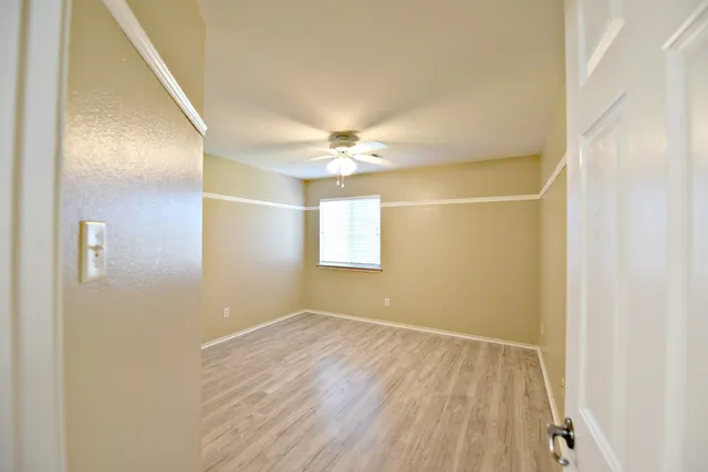 a view of a room with wooden floor and a ceiling fan