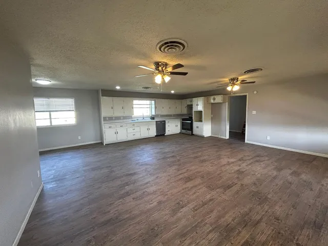 a view of an empty room with a window and a kitchen