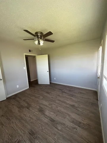 an empty room with a chandelier fan and windows