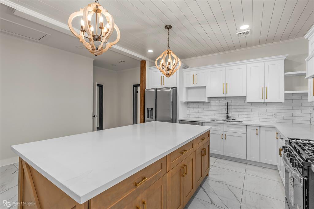 207 Red River Street Benton, LA 71006 - Photo 10 of 29 a kitchen with a refrigerator a sink dishwasher a stove and a dining table with wooden floor