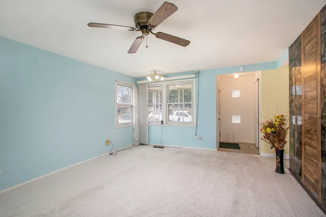 a view of a livingroom with a chandelier fan and windows