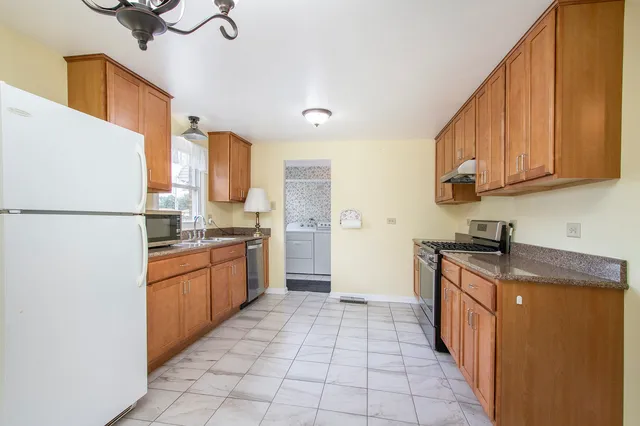 a kitchen with stainless steel appliances granite countertop a refrigerator a stove and a sink