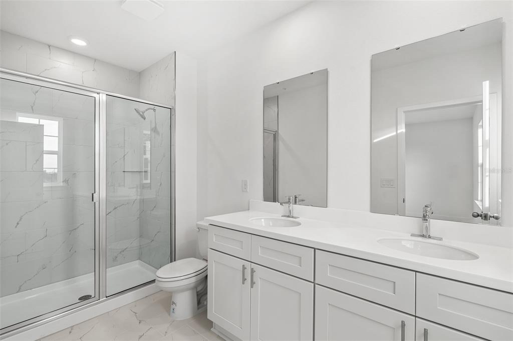 2438 Magnolia Reserve Road Ocoee, FL 34761 - Photo 24 of 26 a bathroom with a shower sink vanity mirror and toilet