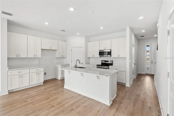 a kitchen with stainless steel appliances granite countertop a stove a refrigerator a sink and white cabinets