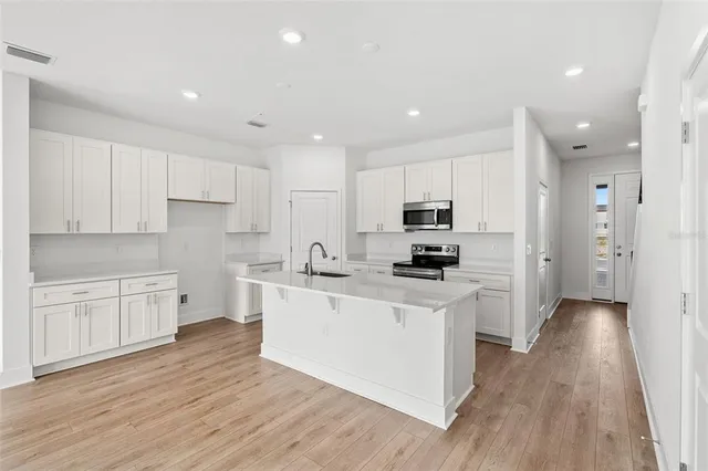 a kitchen with stainless steel appliances granite countertop a stove a refrigerator a sink and white cabinets