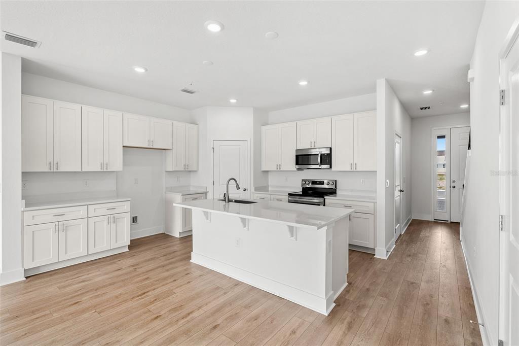 2438 Magnolia Reserve Road Ocoee, FL 34761 - Photo 7 of 26 a large kitchen with stainless steel appliances and white cabinets