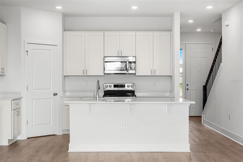 2438 Magnolia Reserve Road Ocoee, FL 34761 - Photo 8 of 26 a kitchen with stainless steel appliances granite countertop a stove a refrigerator a sink and white cabinets
