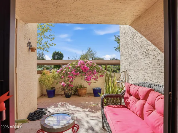 a patio with table and chairs and potted plants