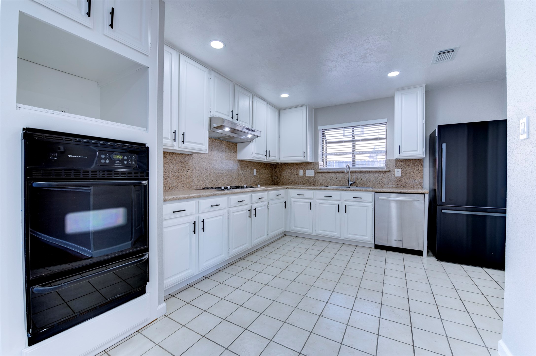 11434 High Bridge Court Houston, TX 77065 - Photo 10 of 31 a kitchen with white cabinets a sink a window and stainless steel appliances