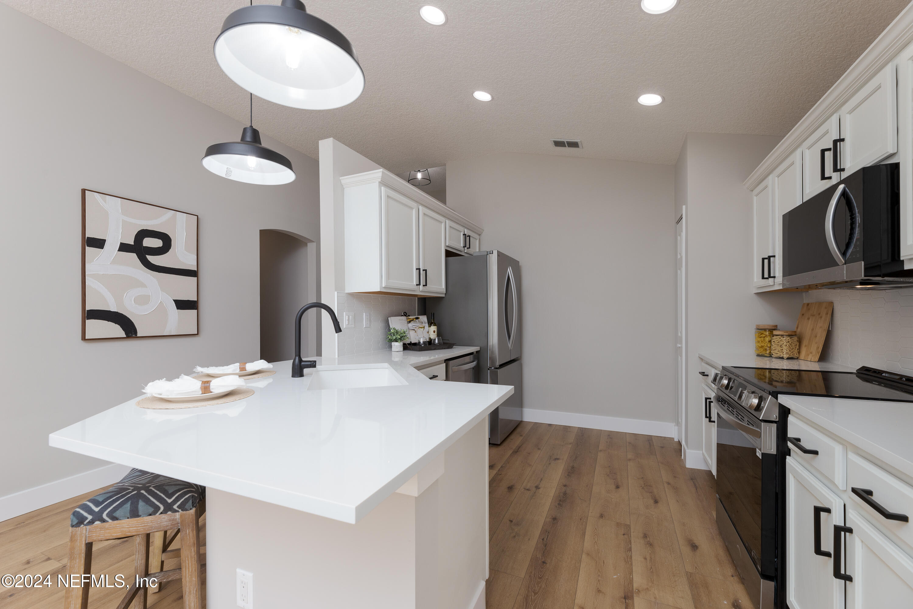 9542 Staples Mill Drive Jacksonville, FL 32244 - Photo 12 of 33 a kitchen with stainless steel appliances kitchen island granite countertop a sink cabinets and wooden floor