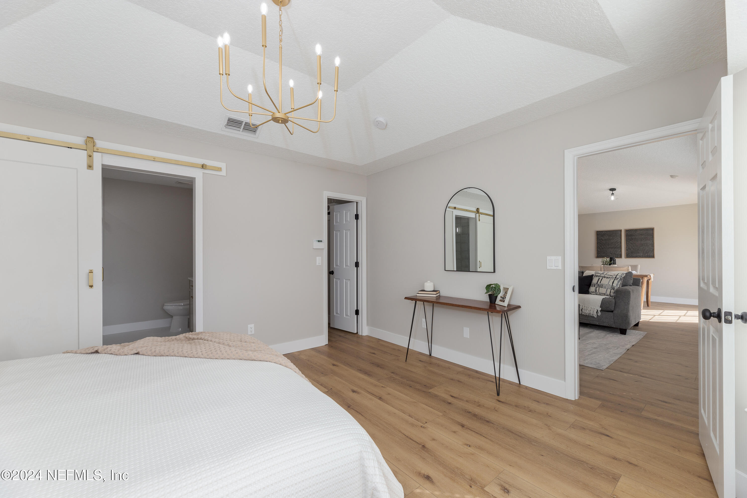 9542 Staples Mill Drive Jacksonville, FL 32244 - Photo 18 of 33 a bedroom with a bed a chandelier and flat screen tv