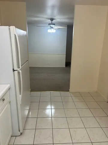 a view of a refrigerator in kitchen and an empty shelves