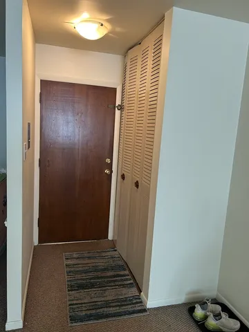 a view of a hallway with wooden floor and a bathroom