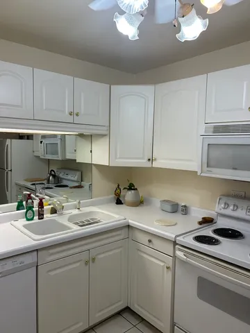a kitchen with a sink white cabinets and white appliances