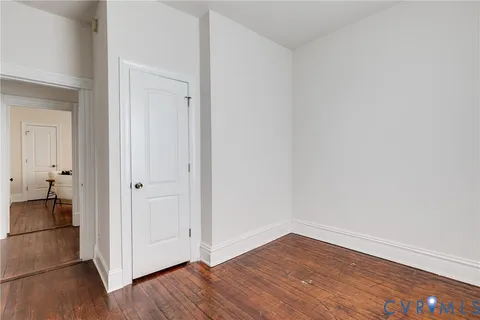 a view of an empty room with wooden floor and closet