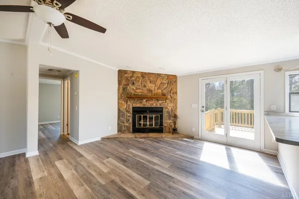 a view of an empty room with wooden floor fireplace and a window