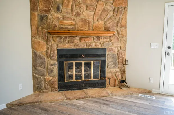 an empty room with wooden floor windows and fireplace