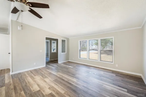 an empty room with wooden floor cabinet and windows