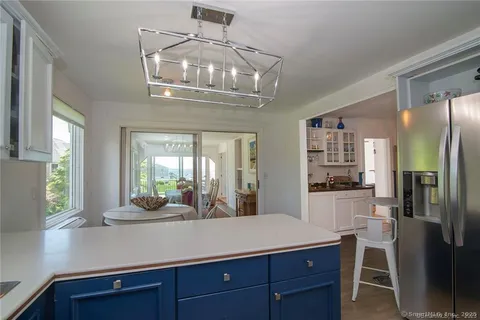 a kitchen with stainless steel appliances a dining table chairs refrigerator and cabinets