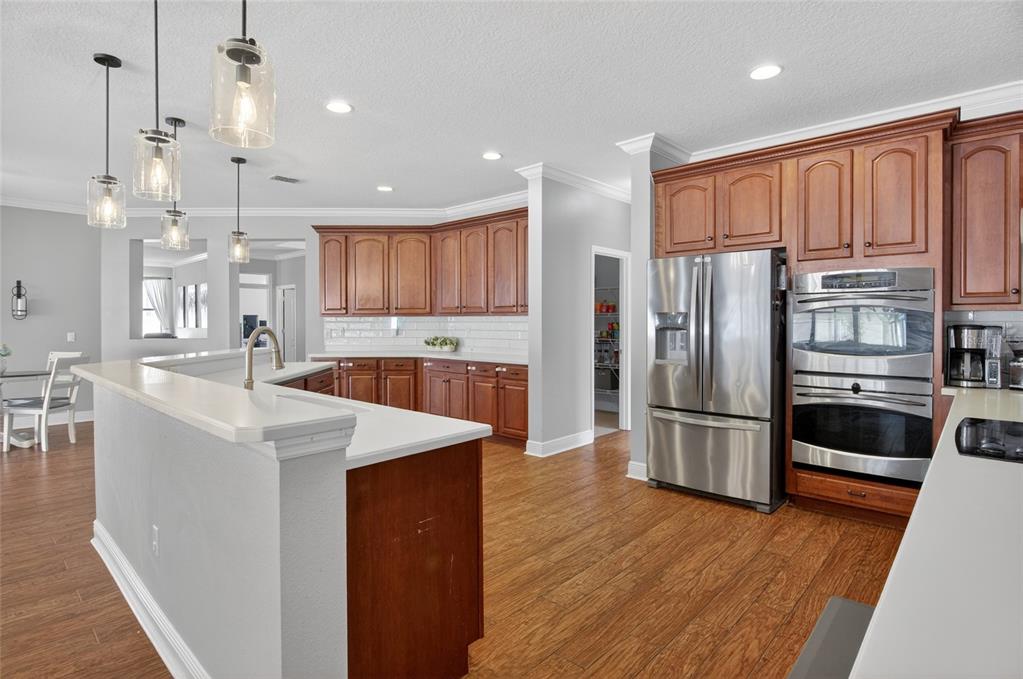 650 Setting Sun Drive Winter Garden, FL 34787 - Photo 13 of 60 a kitchen with stainless steel appliances granite countertop a refrigerator a stove a sink and a oven with wooden floor
