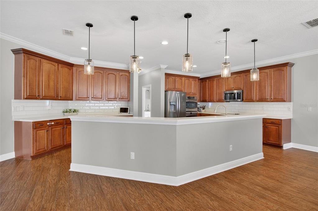 650 Setting Sun Drive Winter Garden, FL 34787 - Photo 14 of 60 a large kitchen with stainless steel appliances granite countertop a refrigerator a oven a kitchen island with wooden cabinets and floors