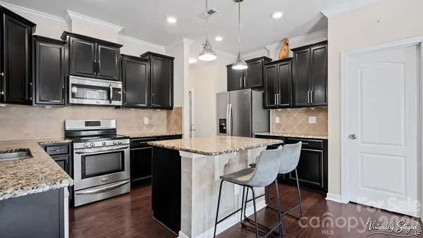a kitchen with stainless steel appliances granite countertop a refrigerator stove microwave and sink