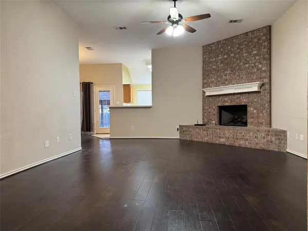 an empty room with wooden floor fireplace and a window