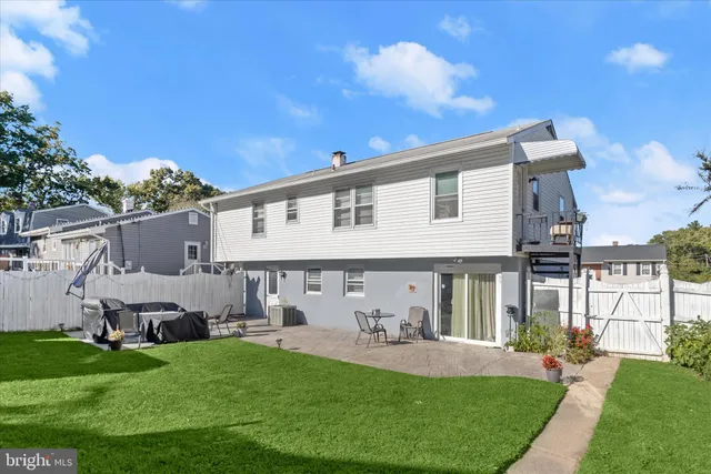 a view of a white house with a small yard and a large tree