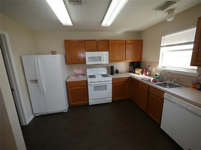 a kitchen with a sink a refrigerator a window and cabinets