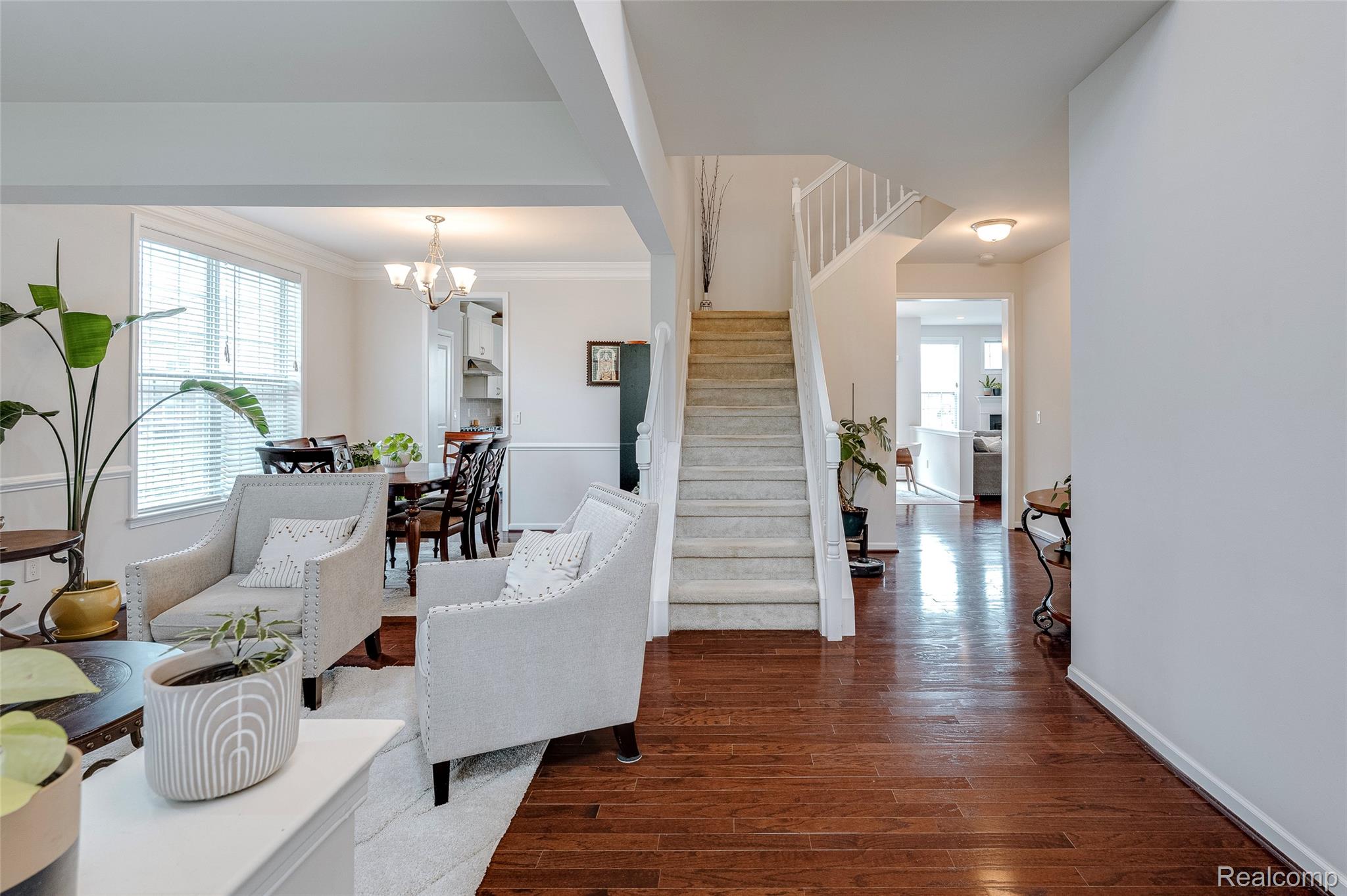 Living room featuring dark wood-type flooring, hanging lights, and crown molding