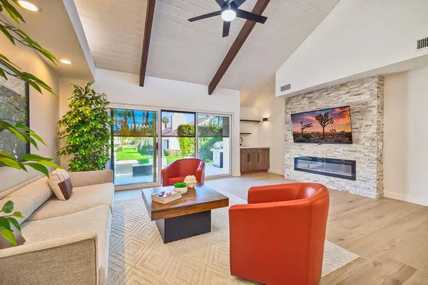 a living room with furniture a flat screen tv and a floor to ceiling window