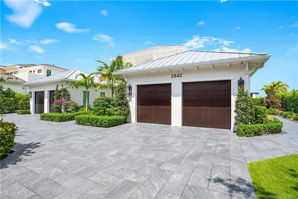 a view of a white house with a yard and potted plants