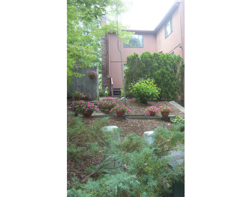 130 Mountain Gate Road, Unit 130 Ashland, MA 01721 - Photo 1 of 12 a backyard of a house with a yard and plants