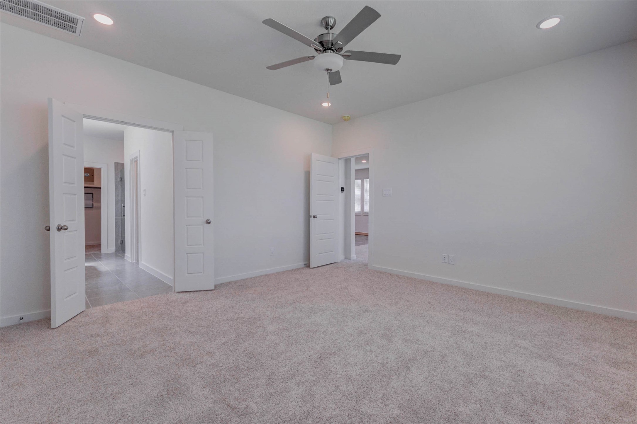 1206 Hemet Court Rosharon, TX 77583 - Photo 11 of 21 Generous primary bedroom featuring plush carpet, neutral paint, recessed lighting, a ceiling fan, and convenient access to nearby bath and hallway areas. The open wall space allows for easy furniture placement, while the simple, modern finishes make the room easy to personalize.