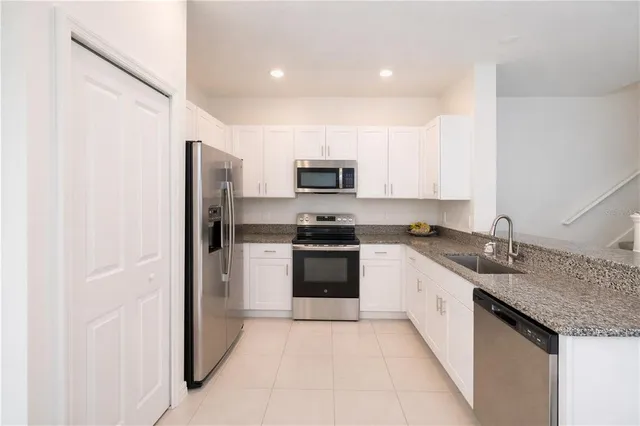 a kitchen with granite countertop a refrigerator and a stove top oven