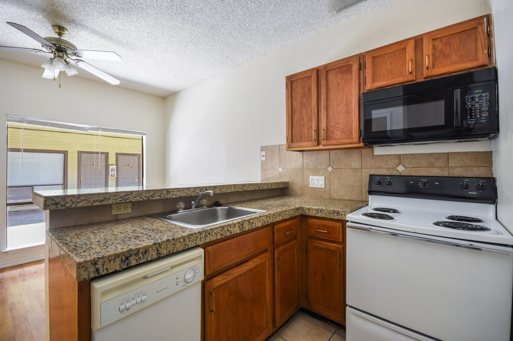 2815 Rio Grande Street, Unit 104 Austin, TX 78705 - Photo 13 of 22 a kitchen with granite countertop a sink and a stove top oven with wooden floor