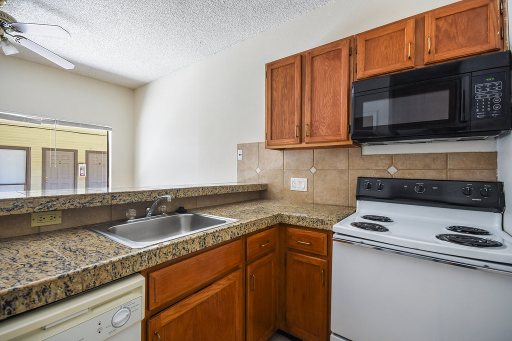 2815 Rio Grande Street, Unit 104 Austin, TX 78705 - Photo 14 of 22 a kitchen with granite countertop a sink and a stove top oven with wooden floor