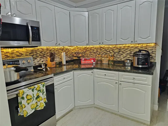 a kitchen with stainless steel appliances granite countertop a stove a sink and a microwave
