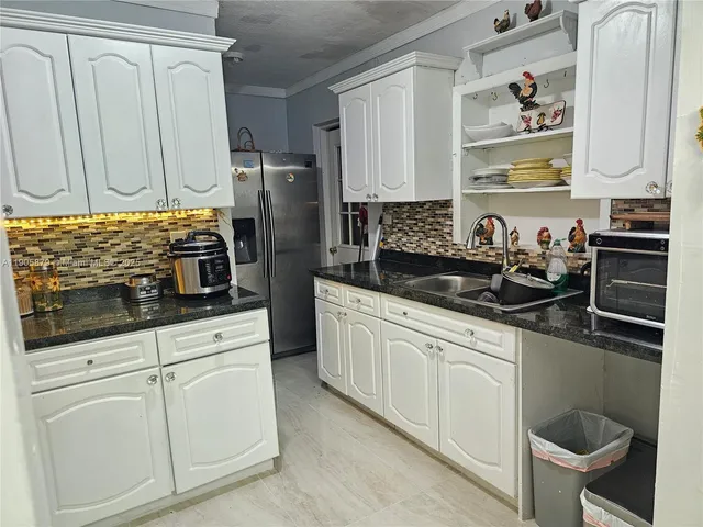 a kitchen with white cabinets and sink
