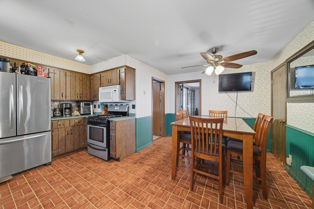 2616 Ridge Road Lansing, IL 60438 - Photo 4 of 25 a kitchen with granite countertop a refrigerator a stove a sink a dining table and chairs with wooden floor