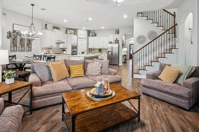 a living room with furniture kitchen view and a wooden floor