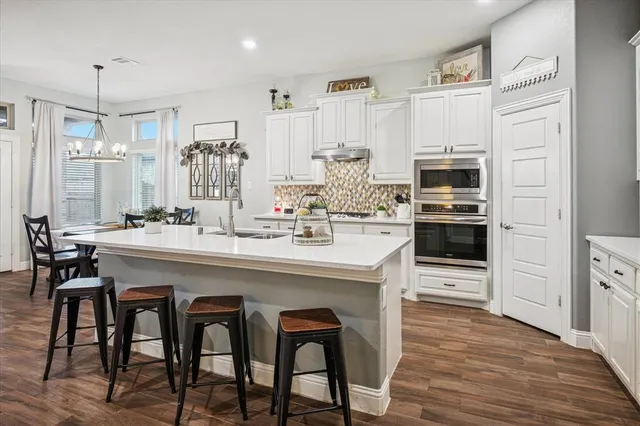 a kitchen with stainless steel appliances kitchen island granite countertop a table chairs and a refrigerator