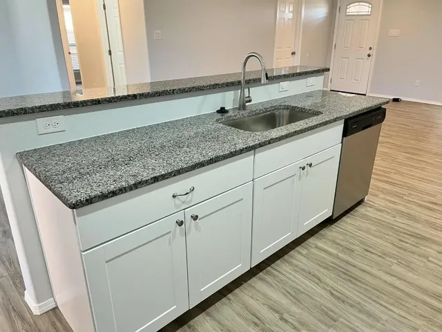 a kitchen with stainless steel appliances granite countertop a sink and a wooden floor