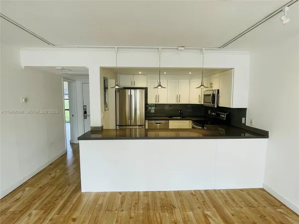 a living room with stainless steel appliances kitchen island granite countertop a sink and wooden floor