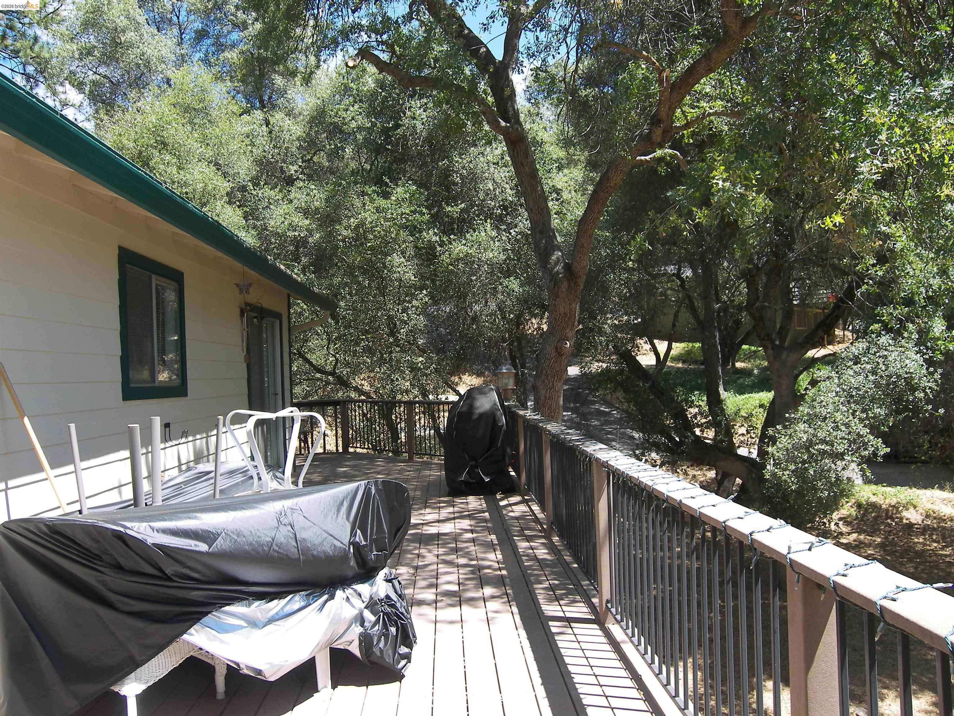 19215 Ferretti Road Groveland, CA 95321 - Photo 33 of 40 Expansive wood-finish deck with dark metal railings, providing an outdoor extension to the home
