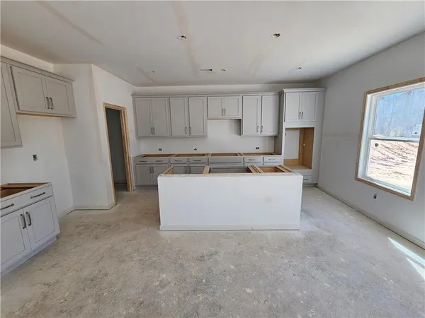 a view of kitchen with stainless steel appliances granite countertop a stove top oven a refrigerator a sink and white cabinets